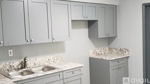 A kitchen with grey cabinets and a marble countertop.