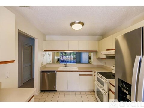 A kitchen with white cabinets and a stainless steel refrigerator.