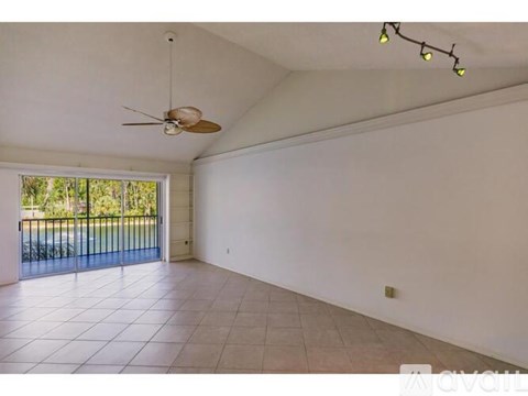 A spacious room with a ceiling fan and sliding glass doors leading to a balcony.