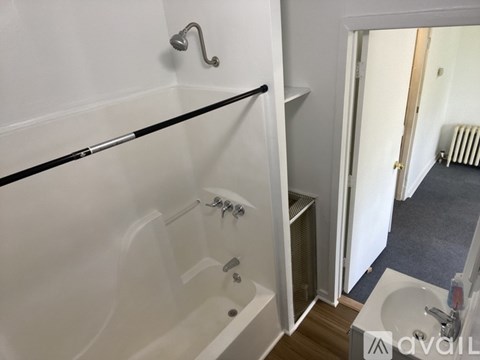 A bathroom with a white tub and a black glass shelf.