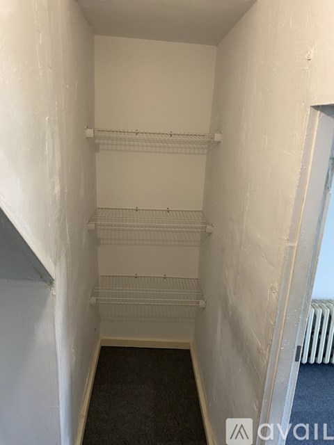 A white hallway with a black carpet and a white wall.
