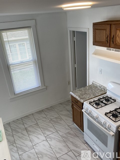 A kitchen with a white gas stove and a window with blinds.
