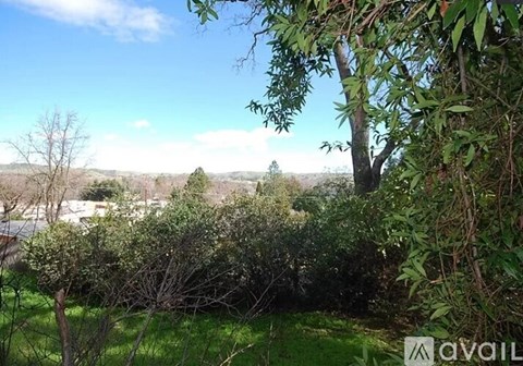 A lush green landscape with trees and a clear blue sky.