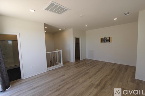 A spacious room with wooden flooring and white walls.