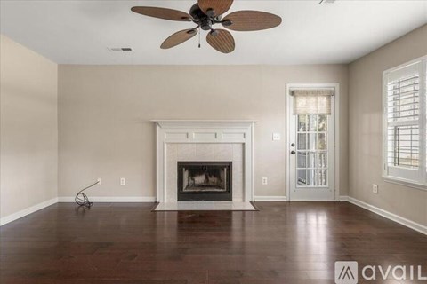 A living room with a fireplace and a ceiling fan.