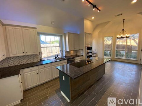 A kitchen with white cabinets and a dark countertop.