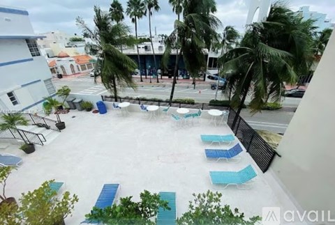 A pool area with blue chairs and palm trees.