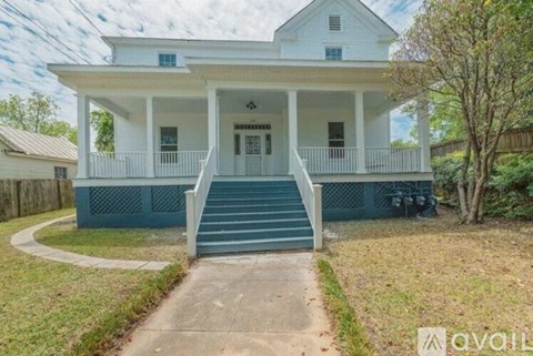 A white house with a porch and a front yard.