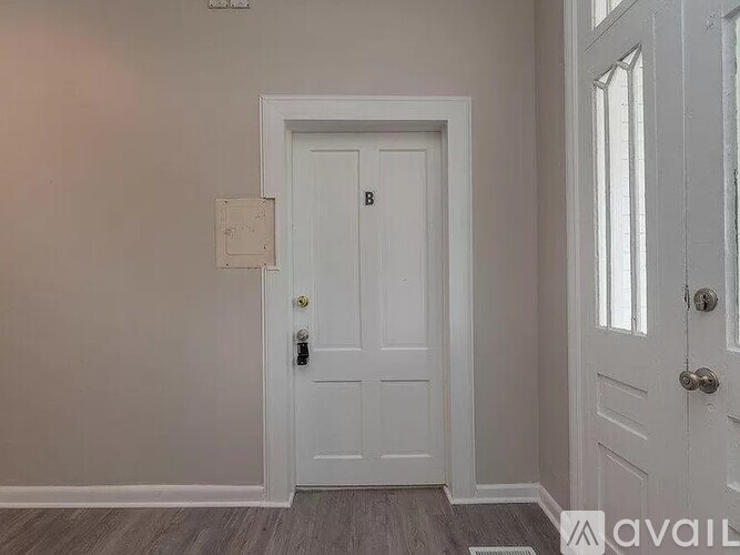 A white door with a gold handle and a keyhole is in a room with a grey floor.