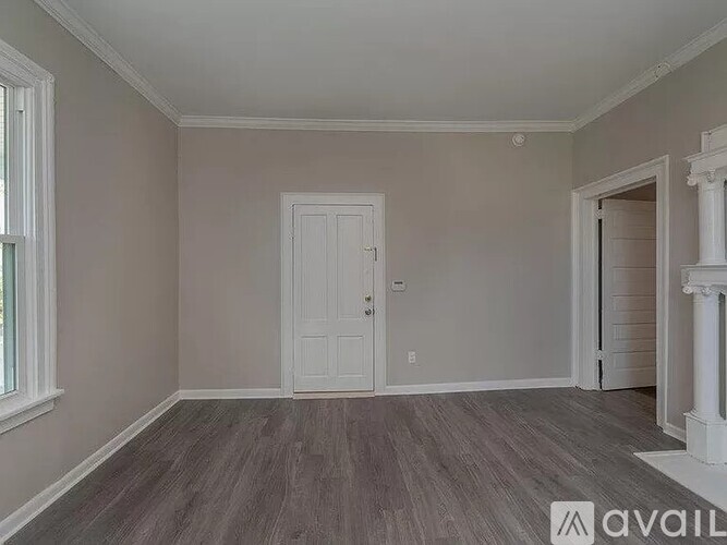 A room with a white door and a window with a grey floor.
