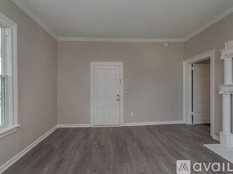 A room with a white door and a window with a grey floor.