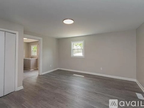 A spacious room with a window and wooden flooring.