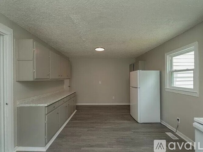 A kitchen with a white refrigerator and cabinets.