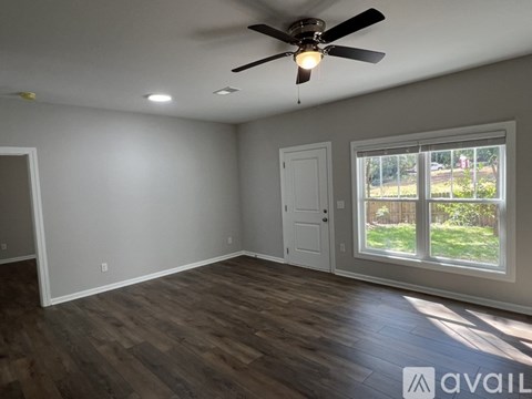 A room with a ceiling fan and a window overlooking a yard.