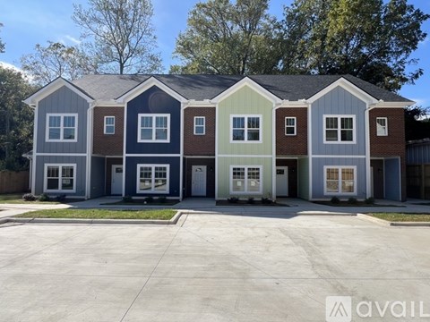 A row of houses with the first one on the left being blue, the second one being grey, the third one being brown, the fourth one being green and the last one being red.