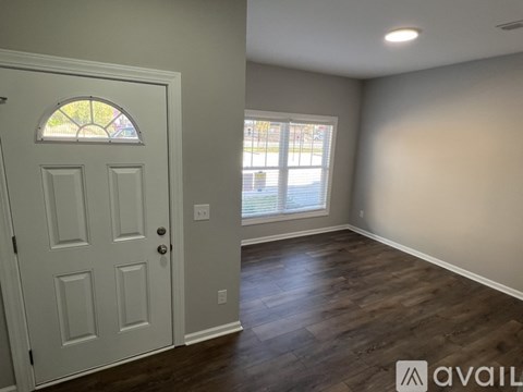 A room with a white door and a window with a view of a street.