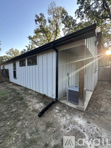 A white metal building with a black roof and a door is shown.