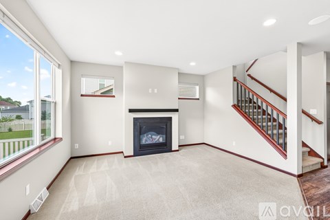 A spacious living room with a fireplace and a staircase.