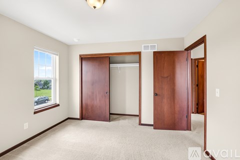 A bedroom with a window and a carpeted floor.