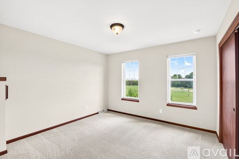 A spacious room with two windows and a carpeted floor.