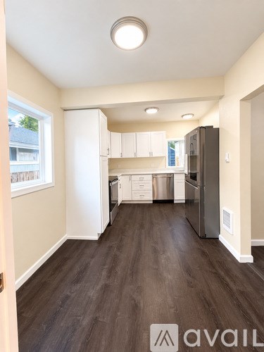 A kitchen with white cabinets and a black fridge.