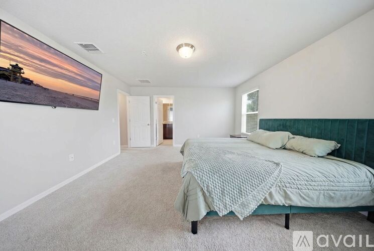 A bedroom with a bed and a painting on the wall.