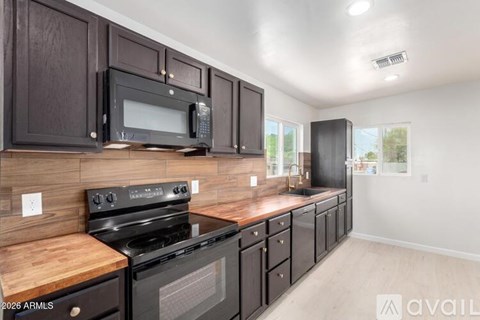A kitchen with dark wood cabinets and black appliances.