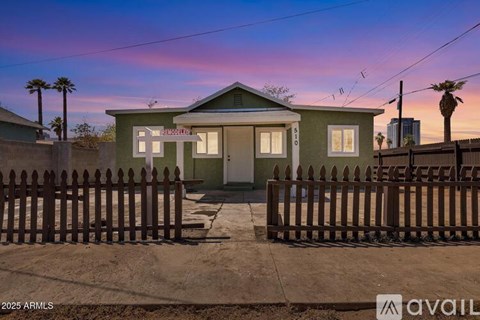 A house with a green exterior and a wooden fence in front of it.