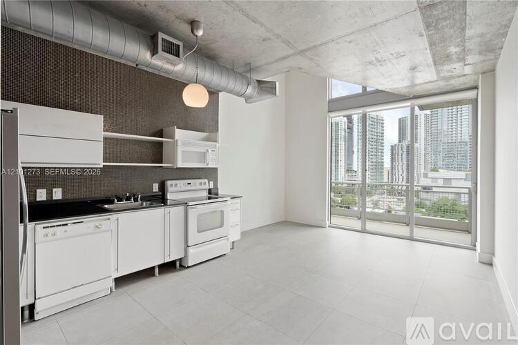 A modern kitchen with white appliances and a view of the city.