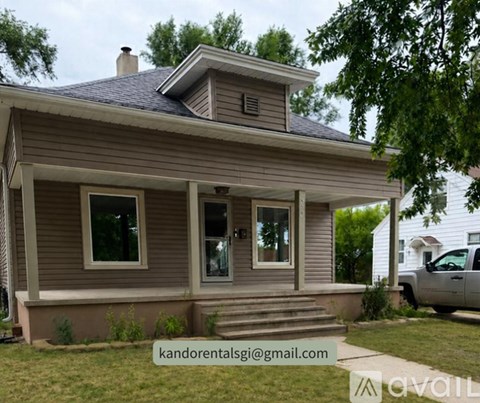 A house with a grey roof and a white car parked in front.