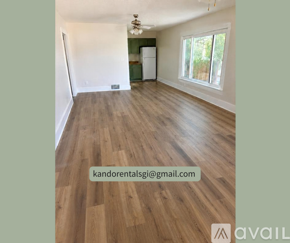 A room with wooden flooring and a window overlooking greenery.
