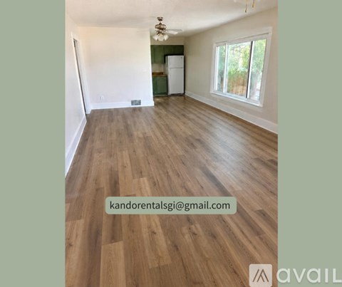 A room with wooden flooring and a window overlooking greenery.