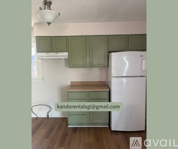 A kitchen with green cabinets and a white refrigerator.