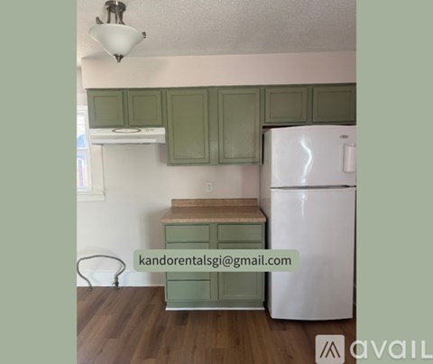 A kitchen with green cabinets and a white refrigerator.