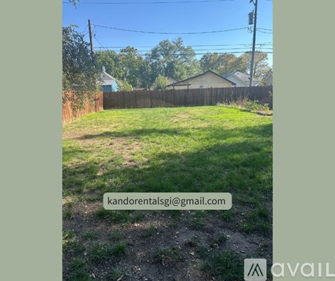 A grassy yard with a fence and houses in the background.