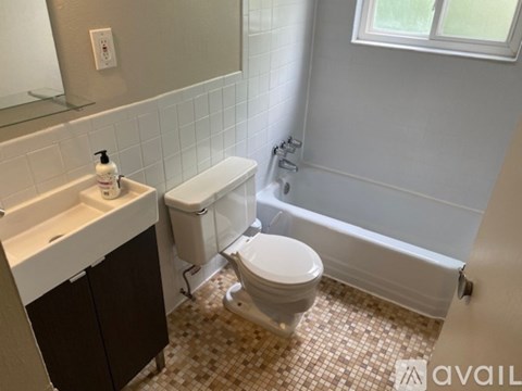 A white toilet is in a bathroom with a white sink and a window.