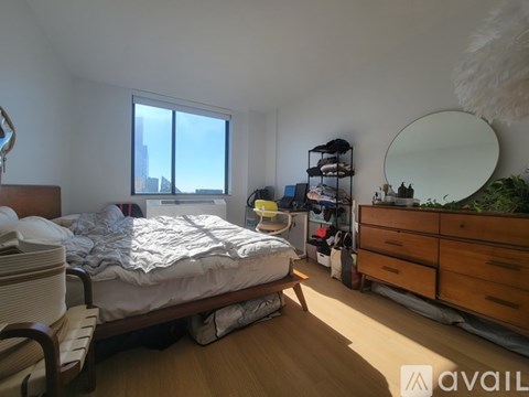 A bedroom with a bed, chair, and a window overlooking the city.