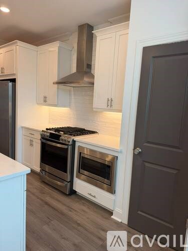 A kitchen with white cabinets and a stainless steel range hood.