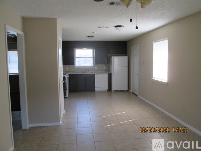 A room with a kitchen area and a refrigerator.