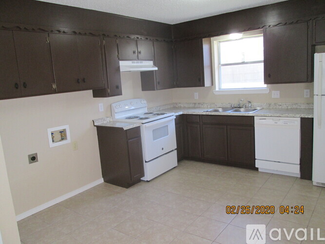 A kitchen with brown cabinets and white appliances.