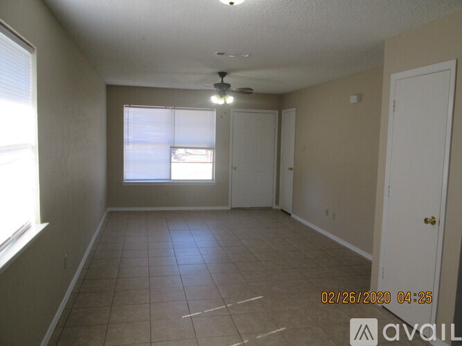 Empty room with a window and a fan on the ceiling.