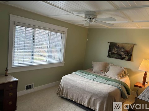 A bedroom with a bed, a dresser, and a ceiling fan.