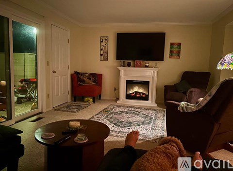 A person is sitting on a couch in a living room with a fireplace and a television.