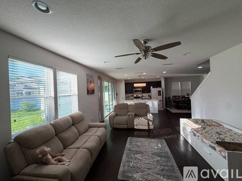 A dog is lying on a beige couch in a spacious living room.