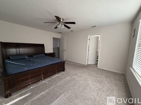 A bedroom with a bed, carpet, and a ceiling fan.