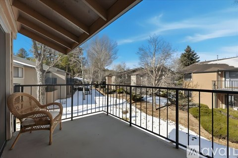 A balcony with a chair and a railing overlooking a pool and houses.