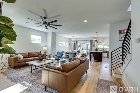 A living room with a brown couch and a ceiling fan.