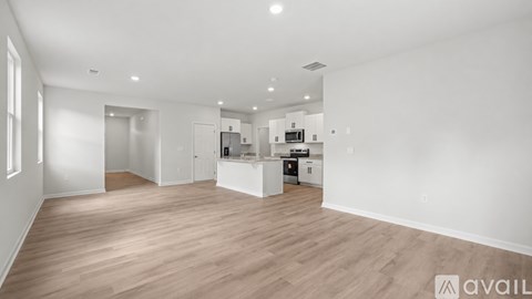A spacious, empty room with wooden flooring and white walls.