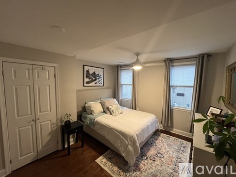 A bedroom with a bed, a table, and a window.