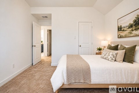 A bedroom with a large bed and a painting on the wall.